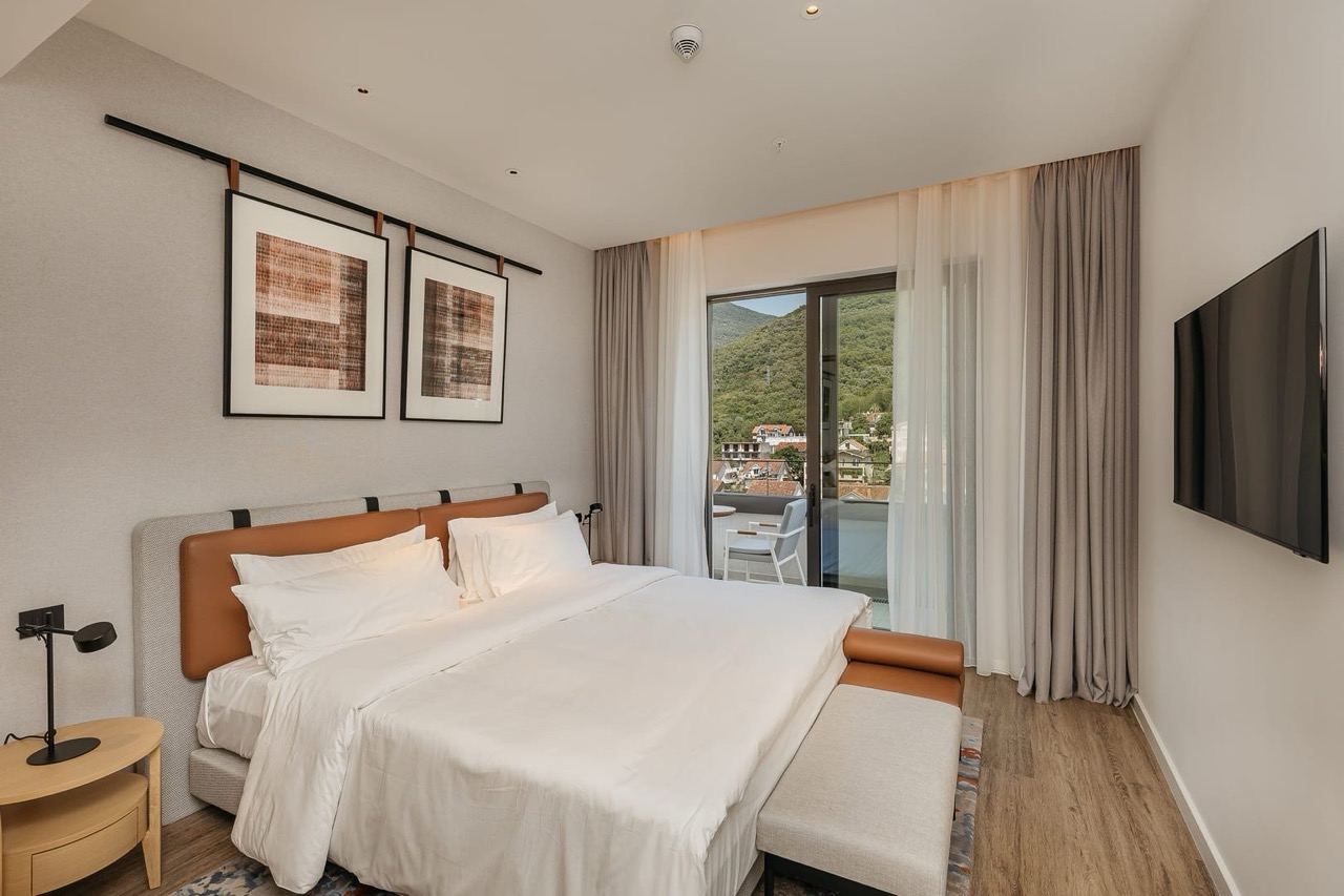 Modern bedroom in Porto Montenegro apartments, Tivat, Montenegro, with mountain views and a terrace.