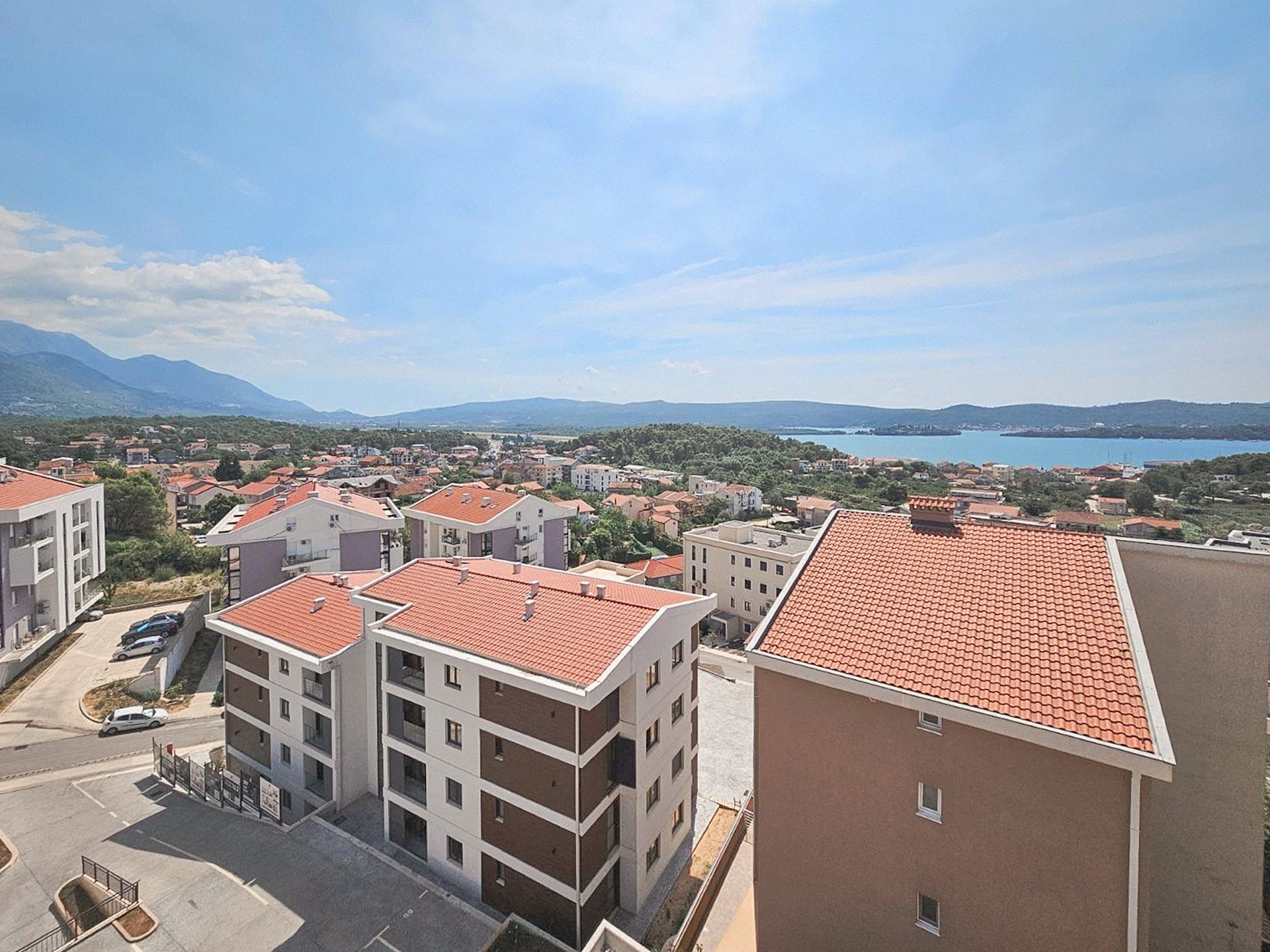 Panoramic view of a residential complex in Tivat, Montenegro: modern houses with tiled roofs and a sea view.