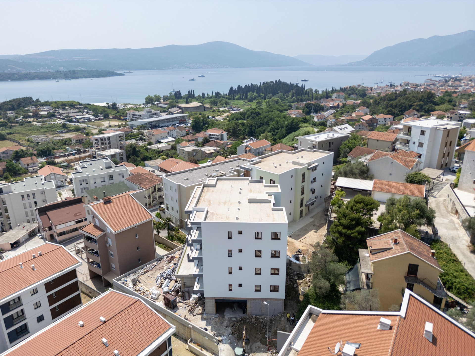Aerial view of a residential complex under construction in Tivat, Montenegro, with panoramic views of the sea and mountains.