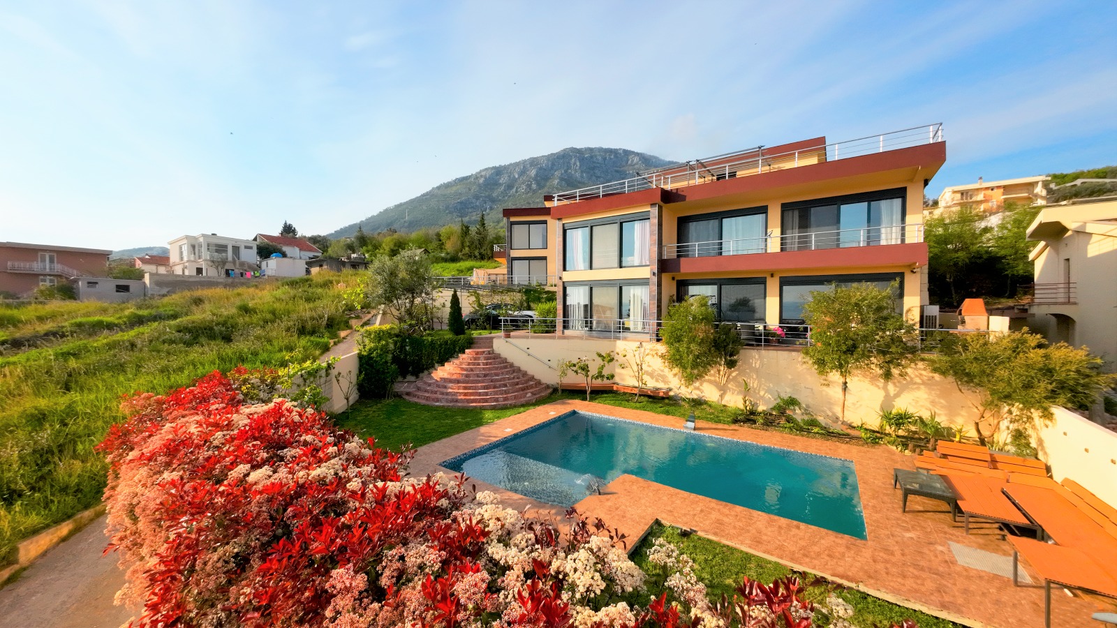 Modern villa in Bar, Montenegro: swimming pool, terrace with sun loungers, landscaped garden, and mountain view.
