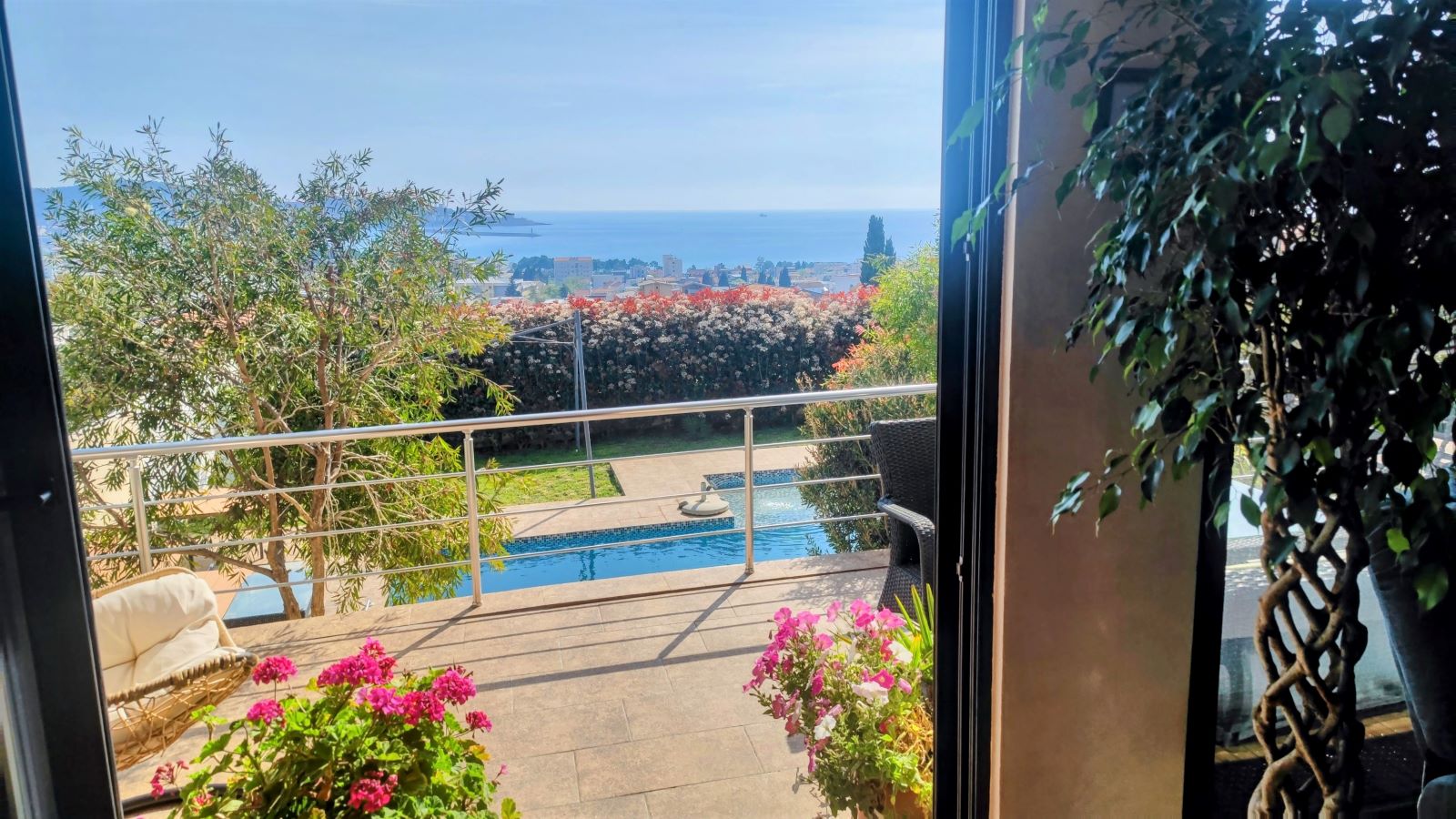 View from the terrace of a villa in Bar, Montenegro: a swimming pool, garden, flowers, and a panoramic view of the sea and the city.