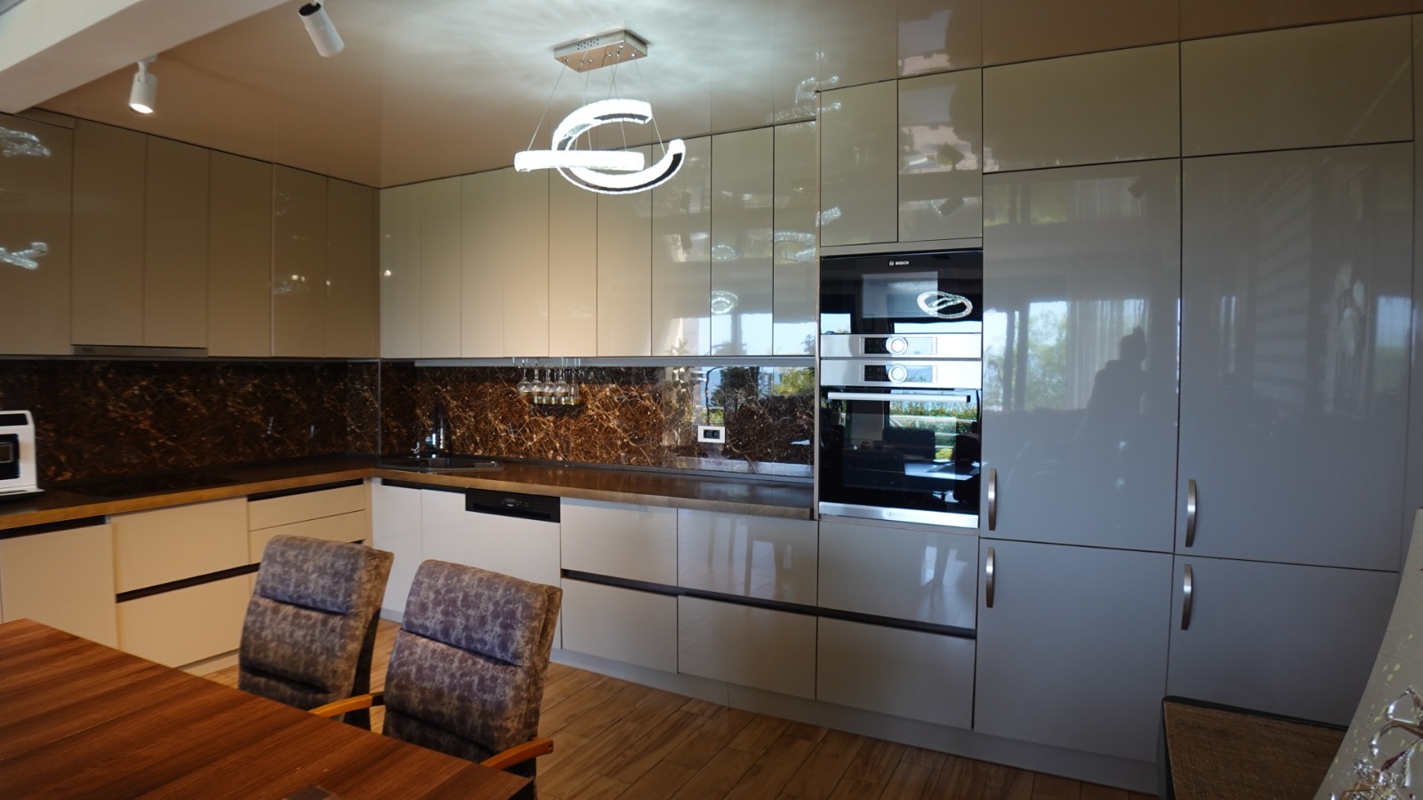 Modern kitchen with glossy fronts and a marble backsplash in a villa in the city of Bar, Montenegro.
