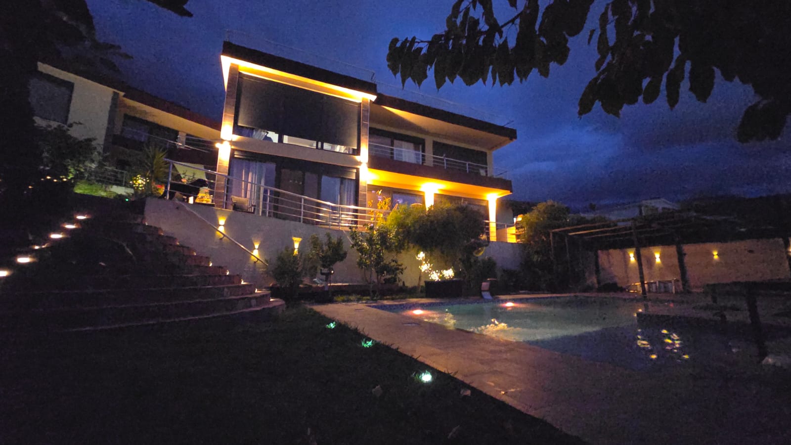 Modern villa in Bar, Montenegro: nighttime facade lighting, terrace, staircase, and outdoor swimming pool in the courtyard.