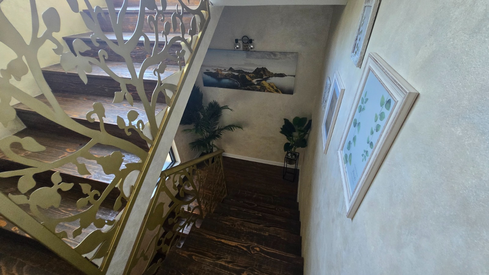 Wooden staircase with ornate railings in the interior of a villa in Bar, Montenegro, with decor and paintings on the walls.