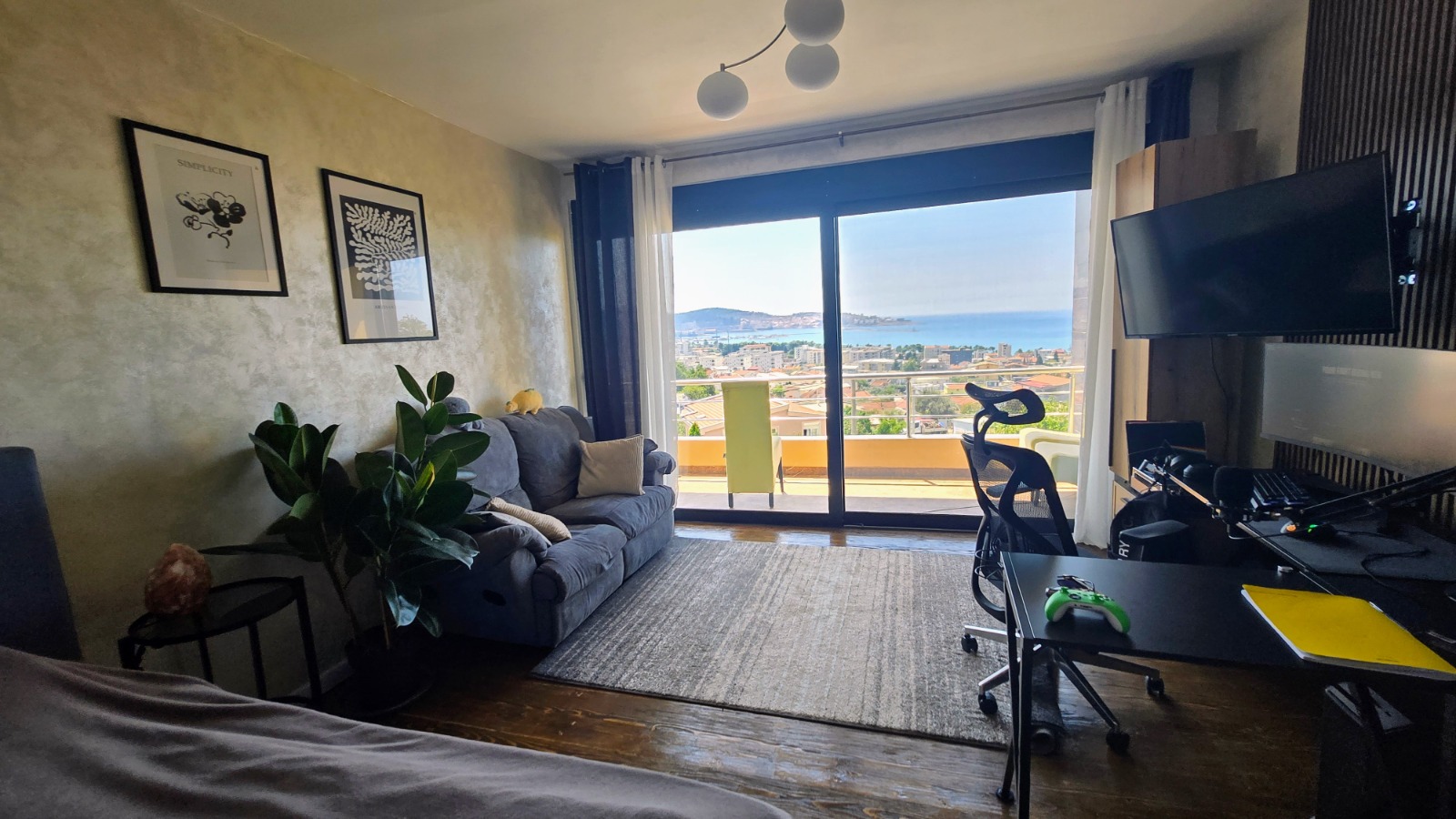 Living room with panoramic sea view in a villa in Bar, Montenegro: a soft sofa, a workspace, and access to the terrace.