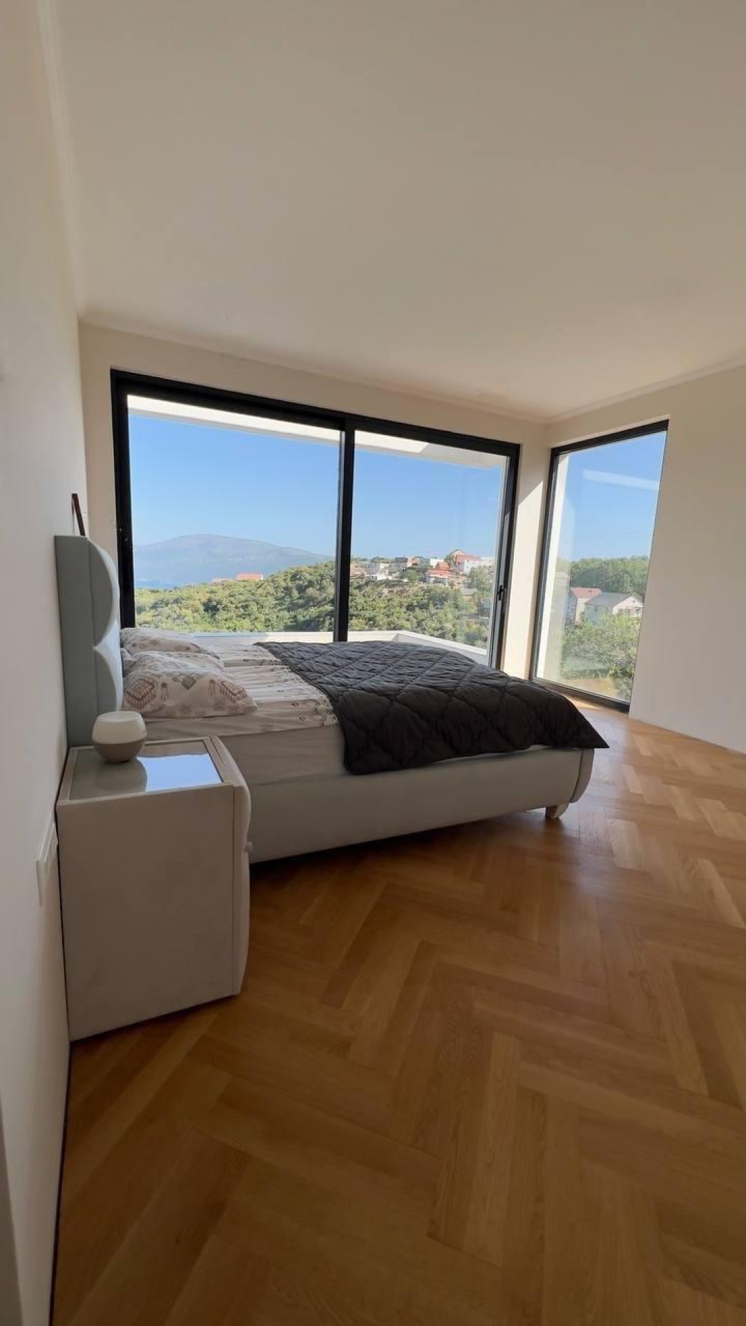 Bedroom with panoramic windows and sea view in a villa complex, Herceg Novi, Montenegro: parquet flooring and modern furniture.