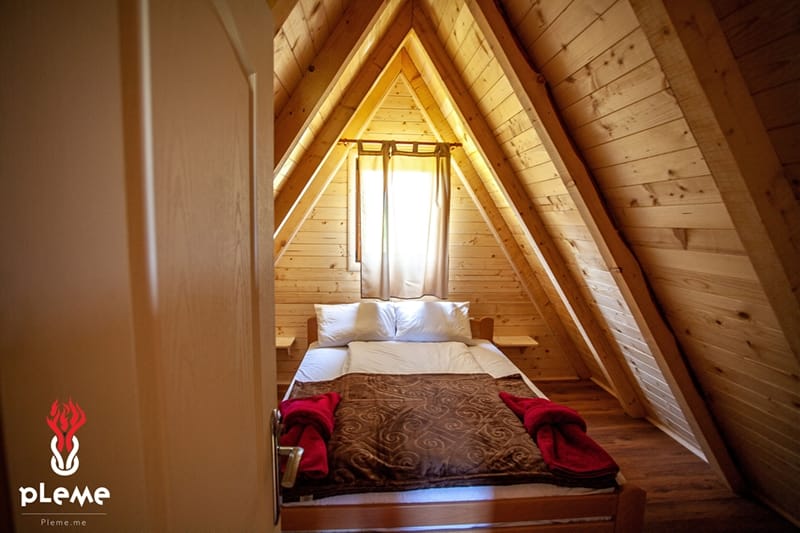 Cozy bedroom in an A-frame wooden house with a double bed in Žabljak, Montenegro. Natural wood finish.