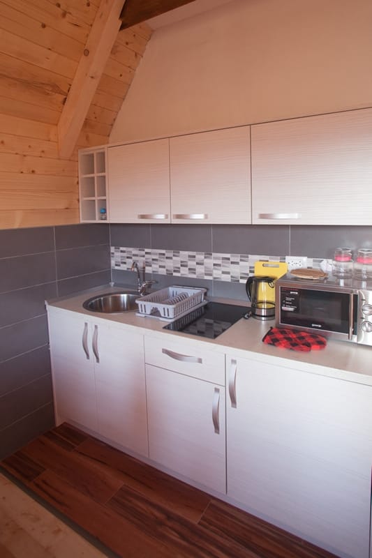 Modern kitchen in a wooden house in Žabljak, Montenegro: light cabinetry, built-in appliances, and wood finishes.