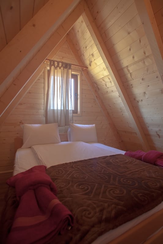 Cozy bedroom in an A-frame wooden house in Žabljak, Montenegro: double bed, light wood finish.
