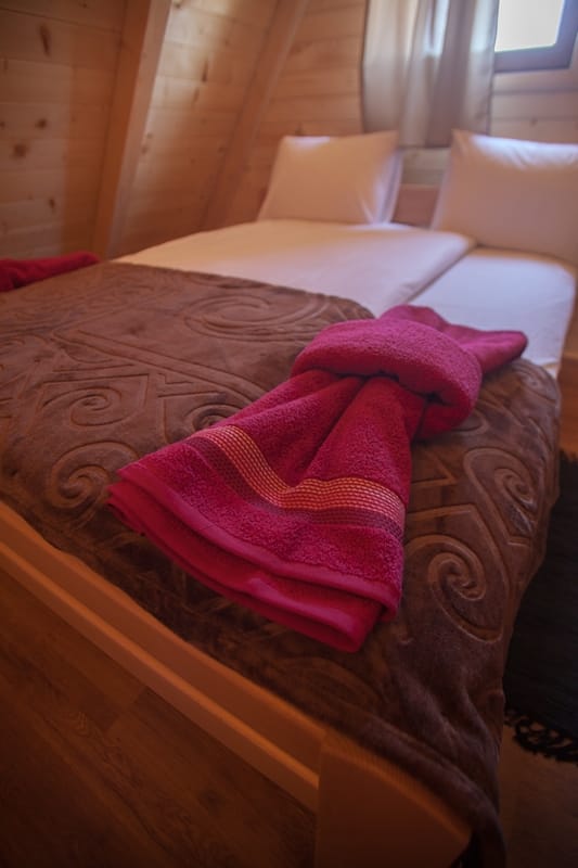 Cozy bedroom with wood paneling in a house in the complex in Žabljak, Montenegro: a double bed with a soft blanket.
