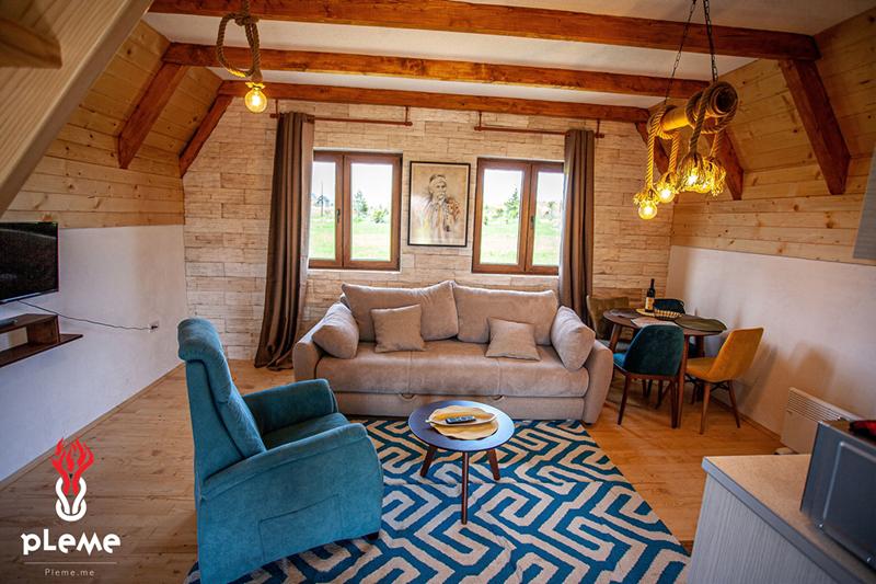 Living room in a wooden house in Žabljak, Montenegro: a cozy interior with beams, a soft sofa, and an armchair.