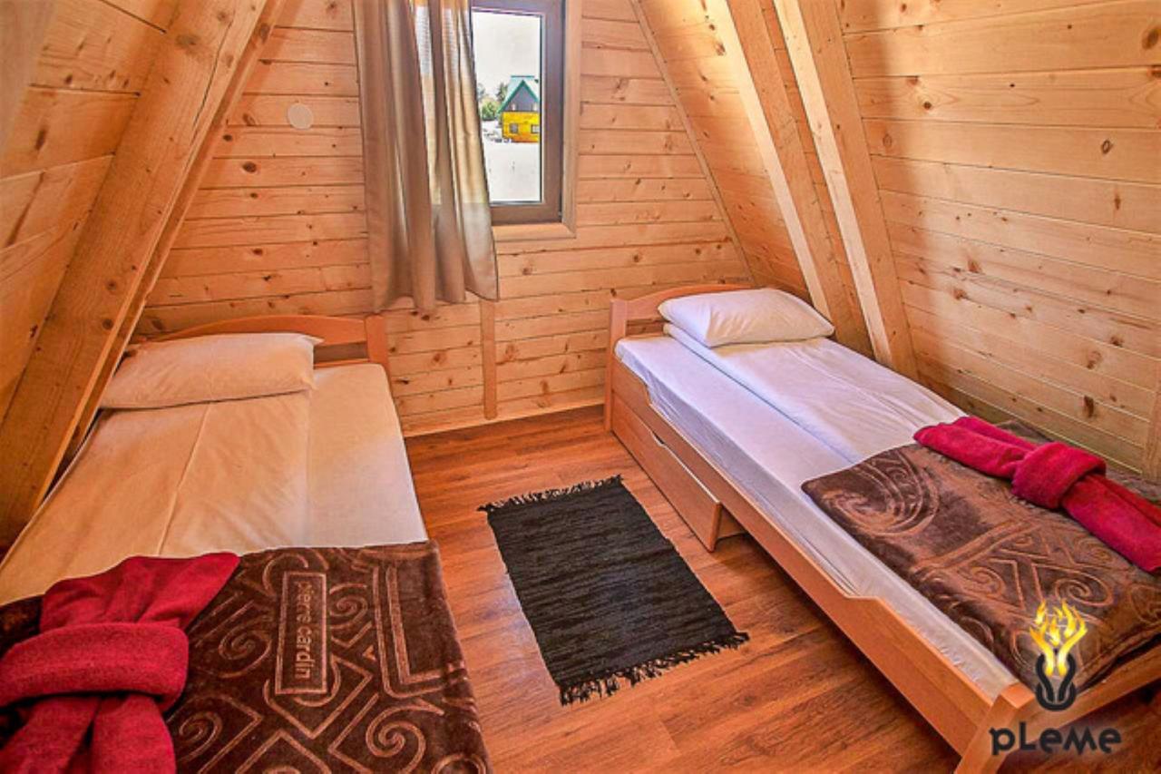 Bedroom in a wooden house in Žabljak, Montenegro: two single beds, wood paneling, and a view from the window.