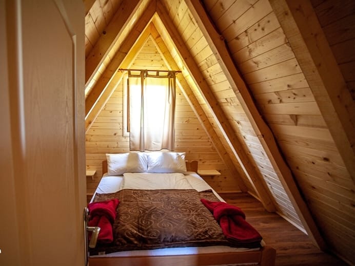 Cozy bedroom in an A-frame wooden house in Žabljak, Montenegro: double bed, wood finish.
