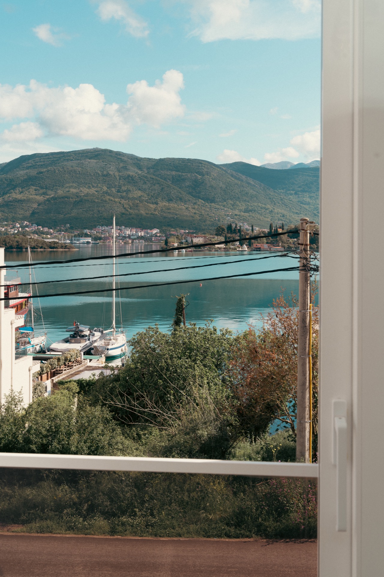 View from the balcony of a townhouse in Luštica over the Bay of Kotor, yachts, and mountains in Montenegro.