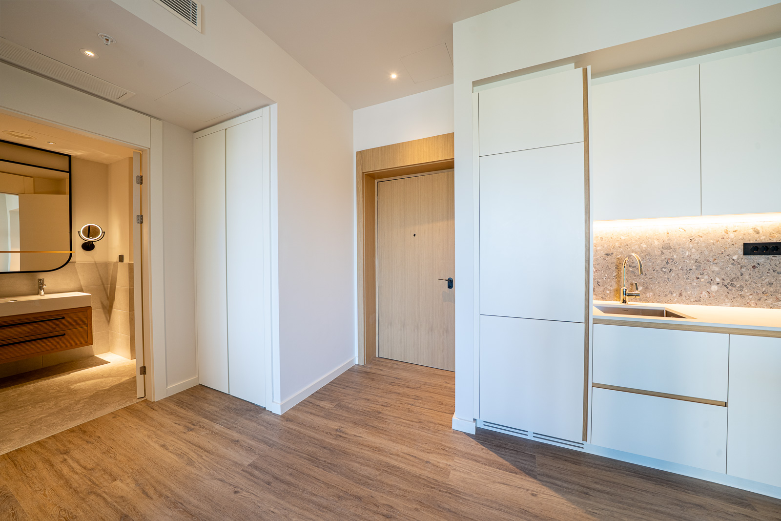 Modern kitchen and hallway in an apartment at Porto Montenegro, Tivat, Montenegro: light furniture, wood finish.