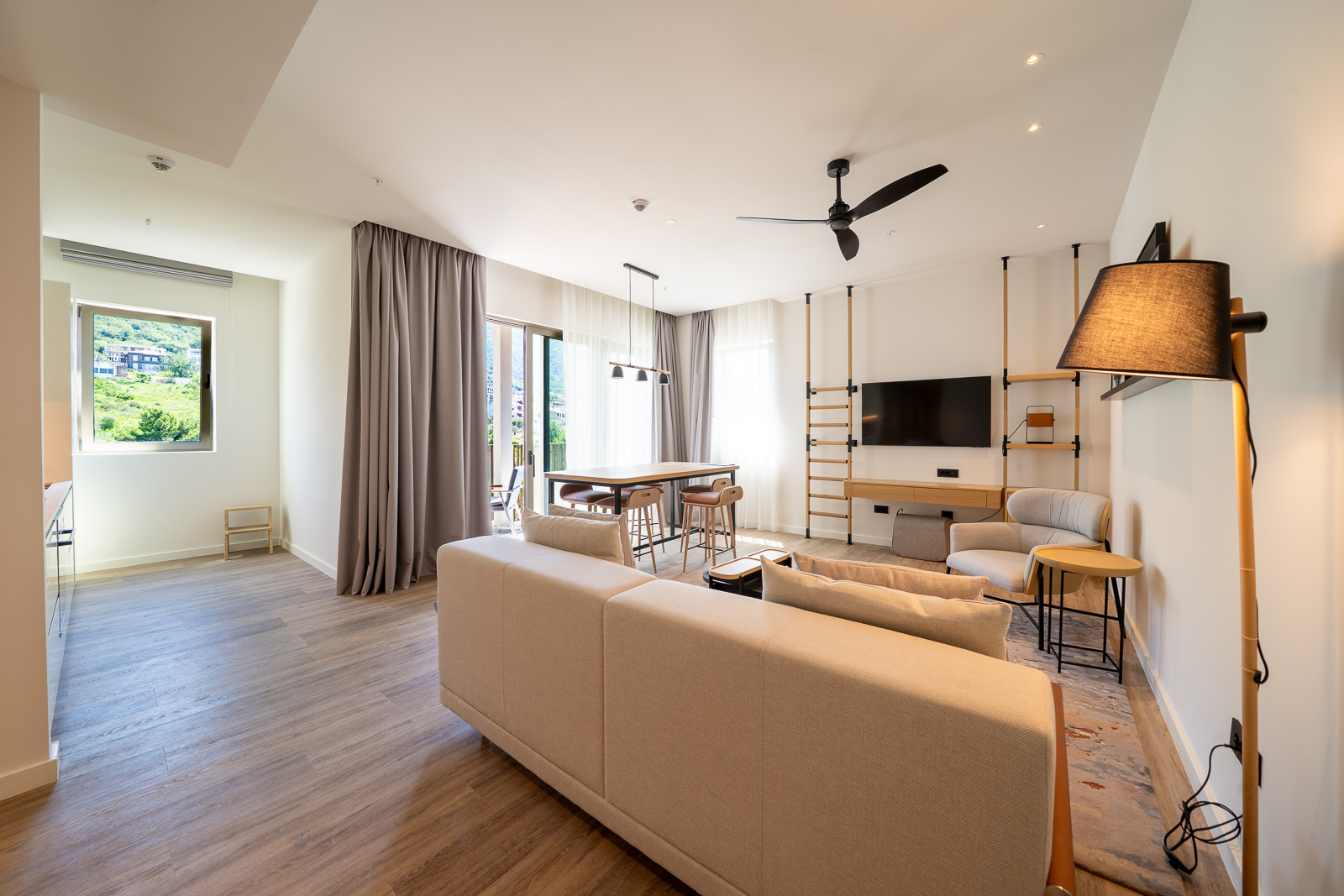 Modern living room in an apartment in Porto Montenegro, Tivat, Montenegro: light-colored furniture, dining area, and mountain view.