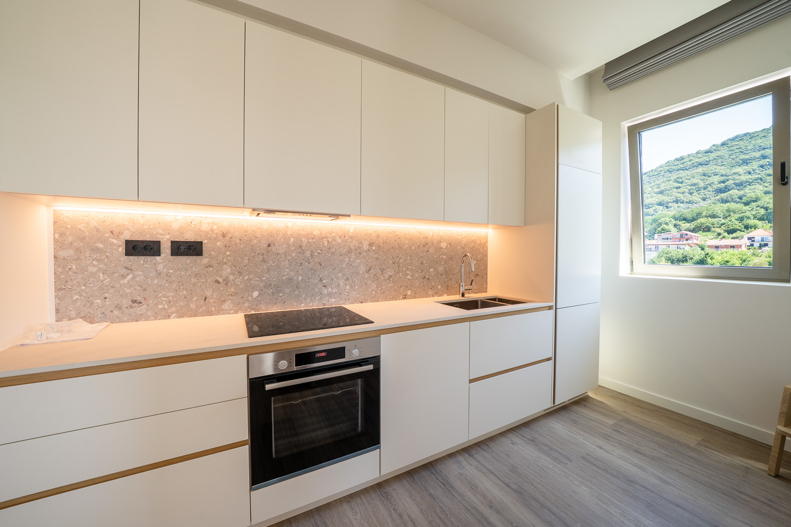 Modern bright kitchen in an apartment in Porto Montenegro, Tivat, Montenegro: built-in appliances and mountain view.