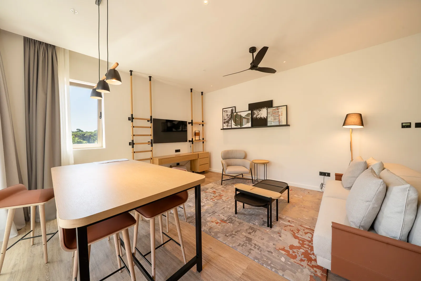 Living room featuring a sofa, coffee table, dining table with stools, and wall-mounted TV.