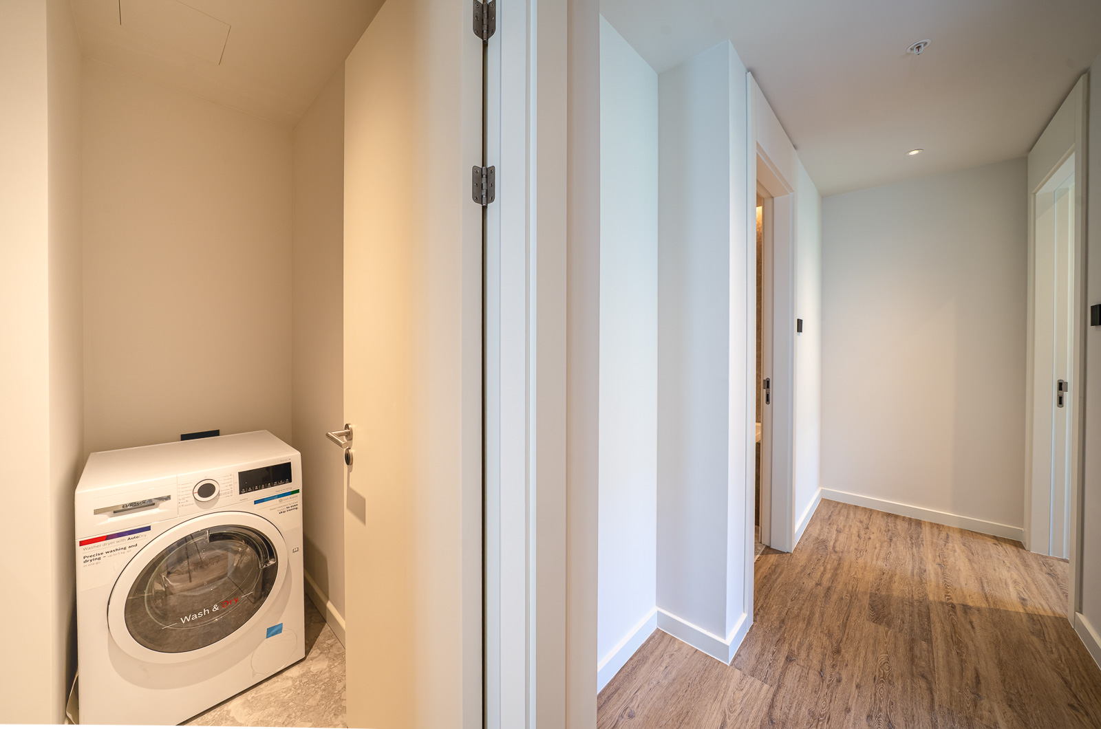 Washing machine in a niche of a modern apartment in Porto Montenegro, Tivat, Montenegro: bright interior, wooden floor.