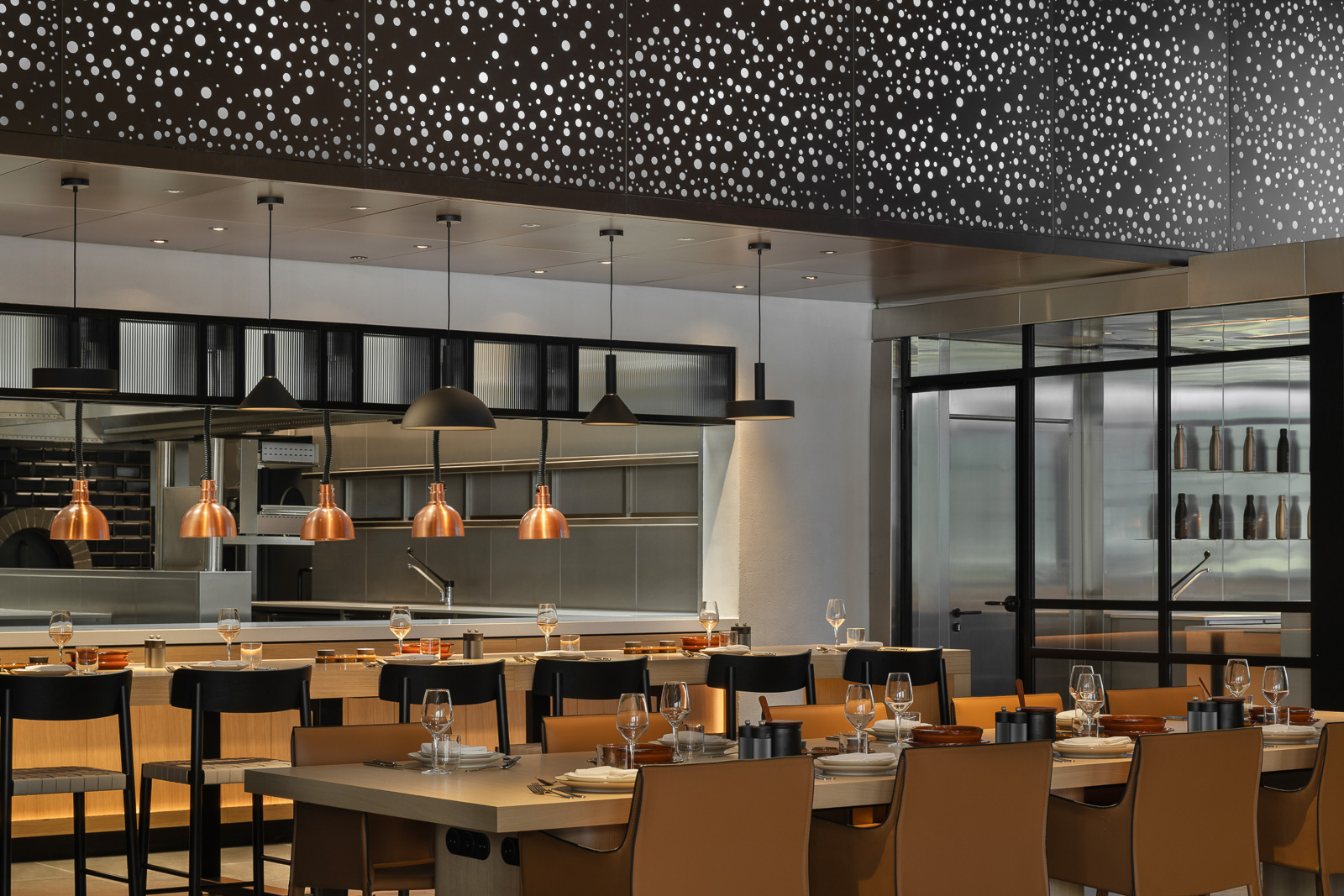 Modern restaurant interior in Porto Montenegro, Tivat, Montenegro: stylish furniture, copper lamps, and an open kitchen.