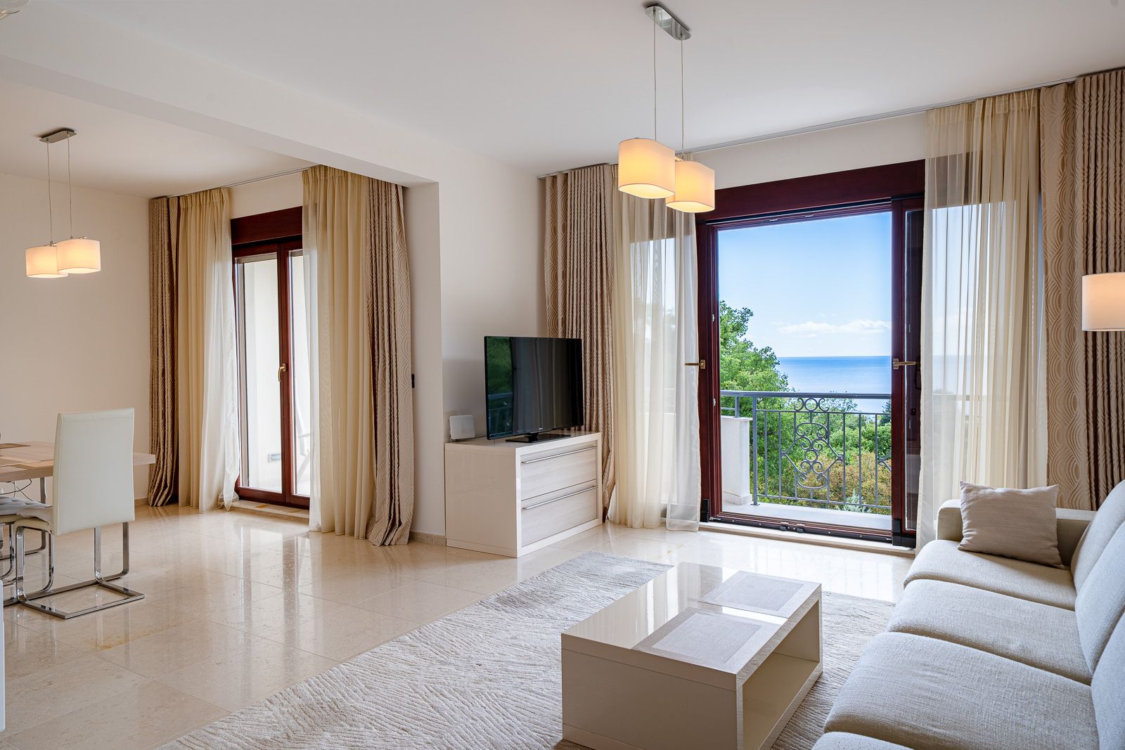 Living room with sea view in an apartment in Petrovac, Montenegro: bright interior, soft furniture, and panoramic windows.