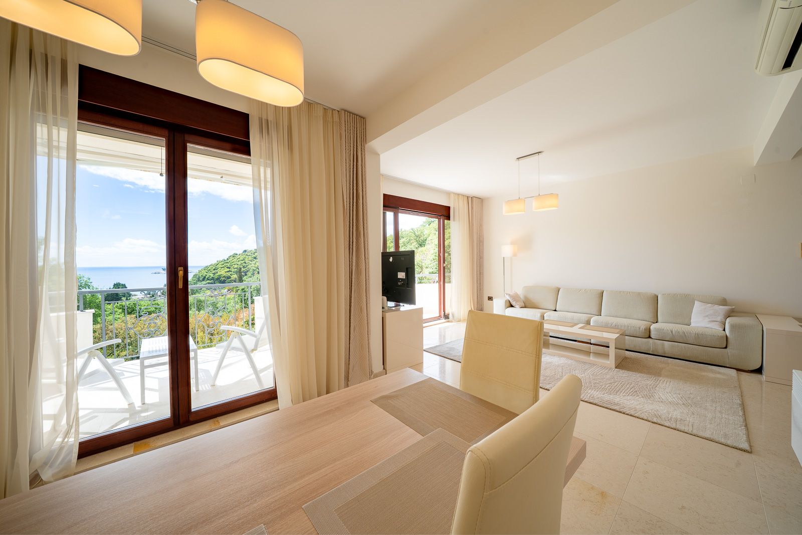 Bright living room with sea view in an apartment in Petrovac, Montenegro: modern furniture, terrace, and panoramic windows.