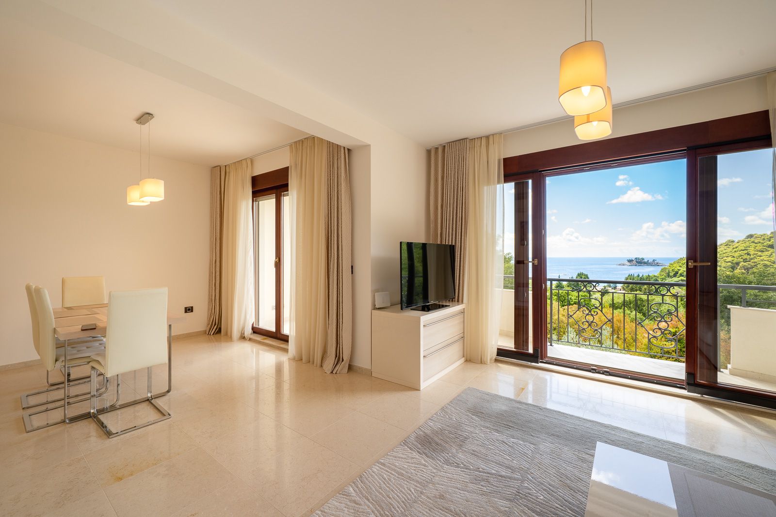 Living room with dining area and panoramic sea view in an apartment in Petrovac, Montenegro: bright interior with furniture.