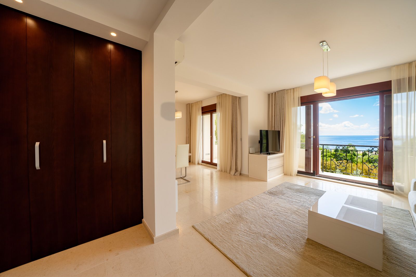 Living room with panoramic sea view in an apartment in Petrovac, Montenegro: bright interior, terrace, and wooden furniture.