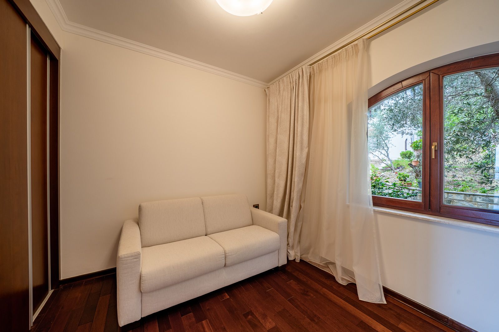 Bright living room with a sofa and garden view in an apartment in Petrovac, Montenegro: parquet flooring, built-in wardrobe, and a cozy interior.