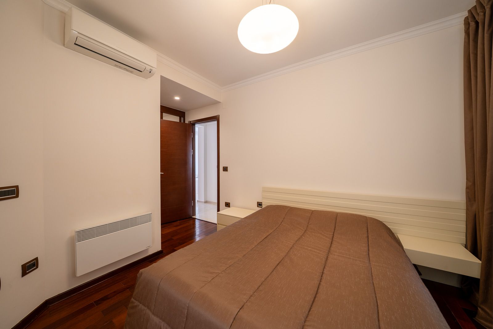 Bright bedroom with a double bed, air conditioning, and parquet flooring in an apartment for sale in Petrovac, Montenegro.