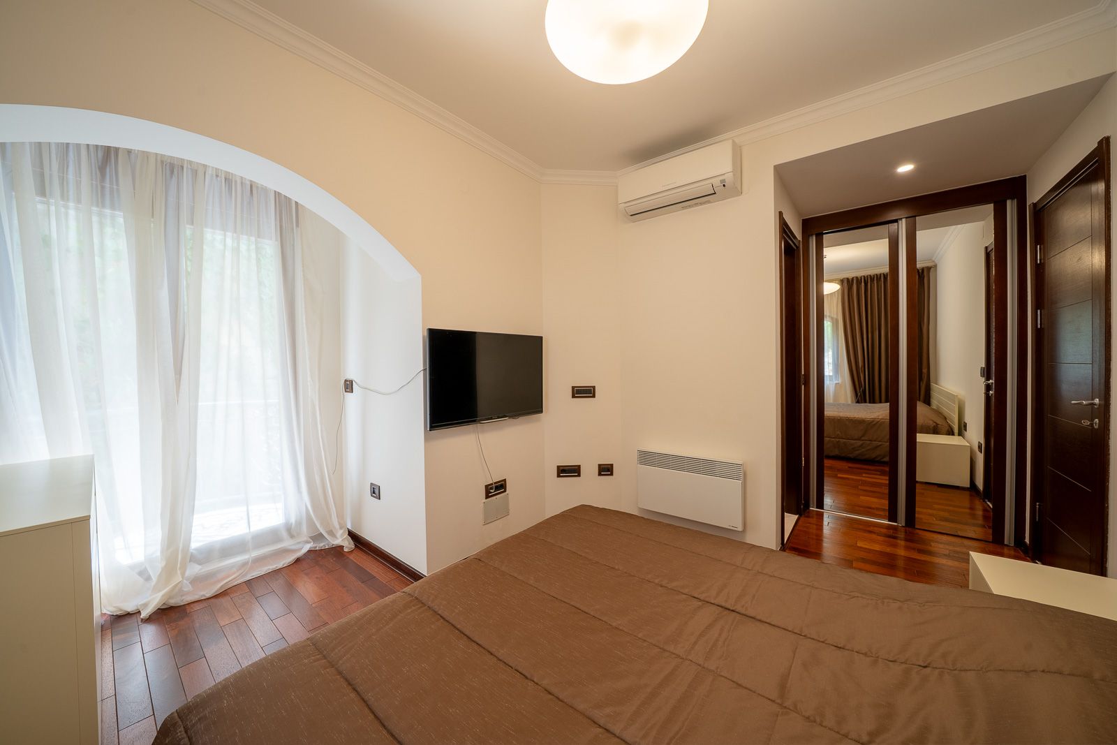 Bedroom in an apartment in Petrovac, Montenegro: double bed, TV, mirrored wardrobe, and parquet flooring.