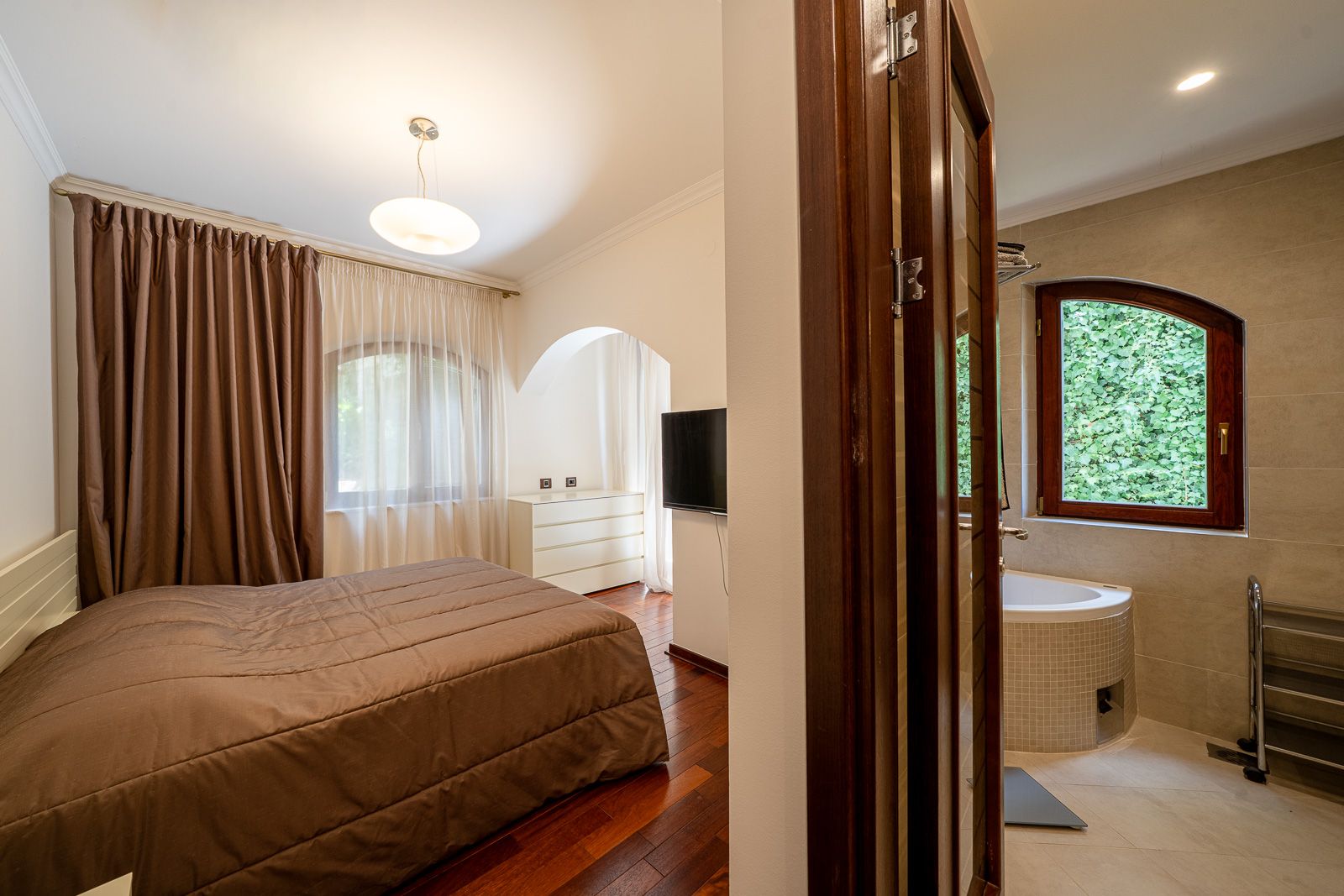 Bedroom with a double bed and bathroom in an apartment in Petrovac, Montenegro: modern interior and garden view.