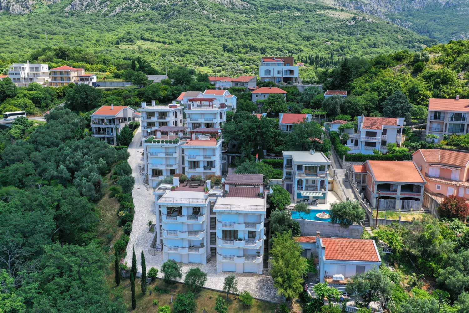 Aerial view of a residential complex with a pool and terraces in Petrovac, Montenegro: modern apartments surrounded by greenery.