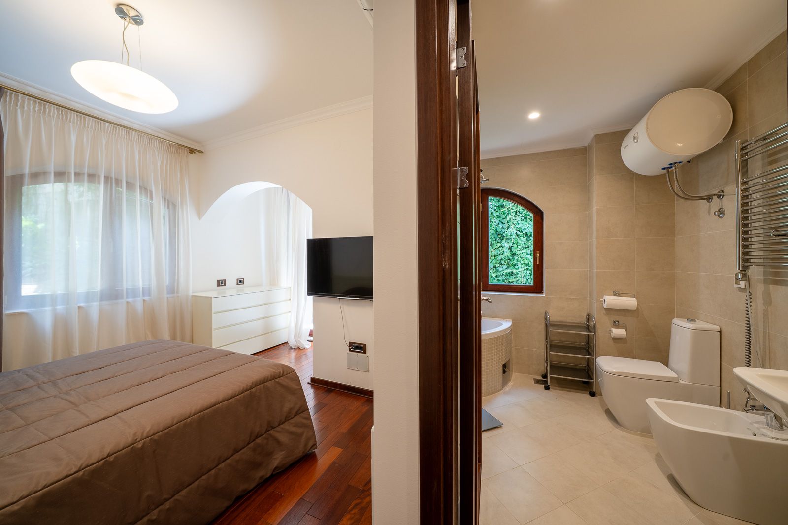 Bedroom and bathroom interior in an apartment, Petrovac, Montenegro: double bed, TV, and modern fixtures.