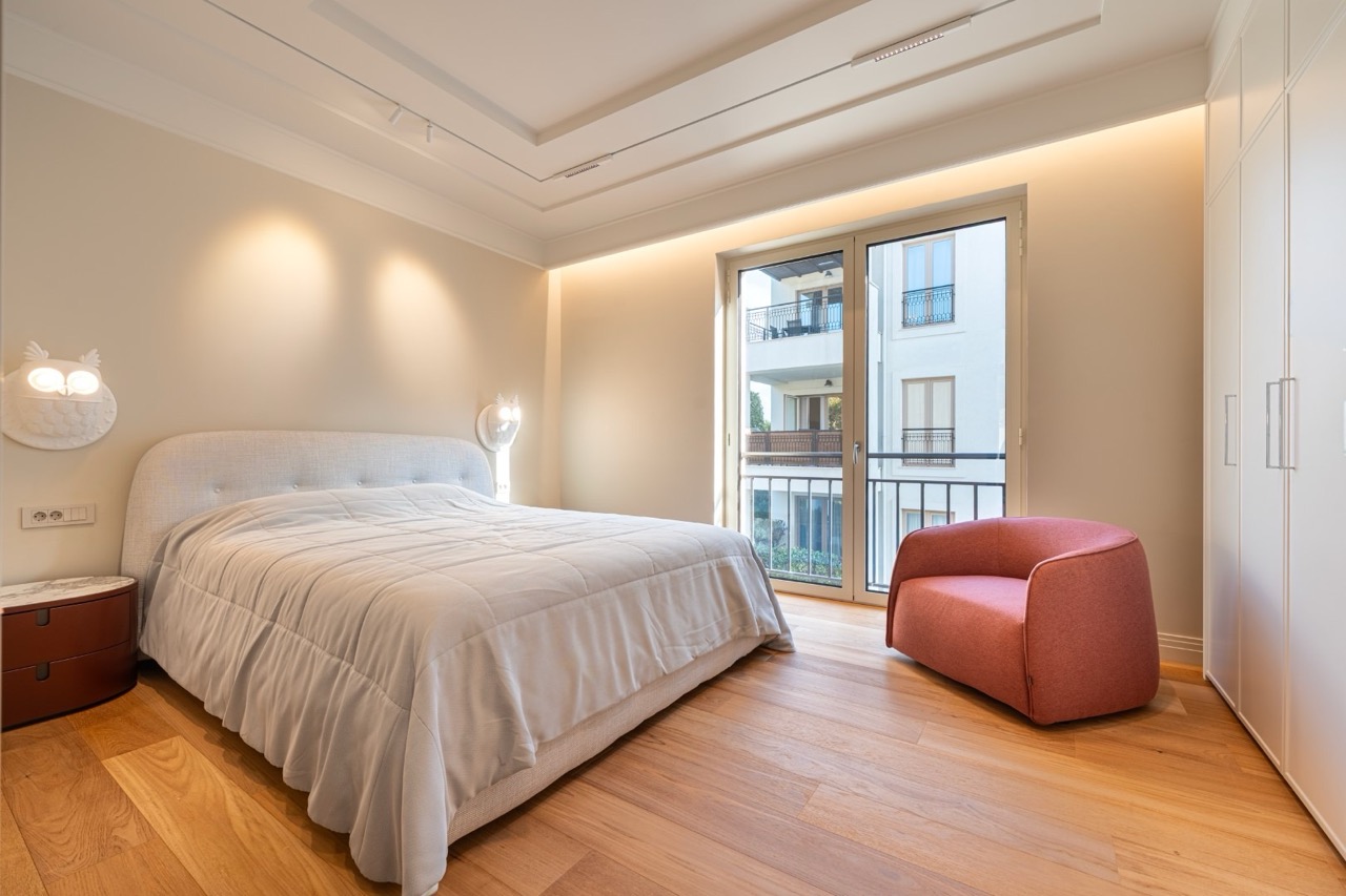Modern bedroom in an apartment in Porto Montenegro, Tivat, Montenegro: a double bed, a pink armchair, and a view of the terrace.