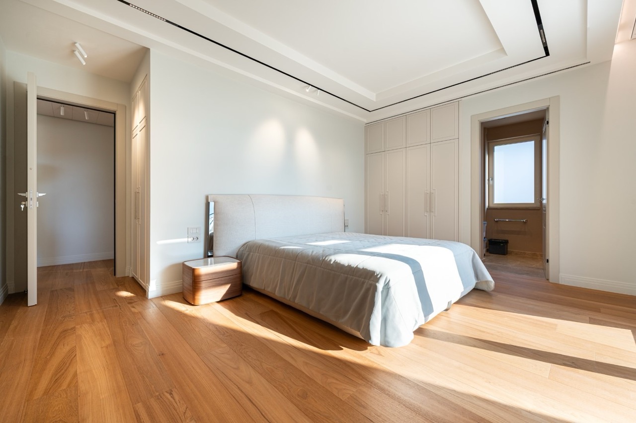 Modern bedroom in an apartment in Porto Montenegro, Tivat, Montenegro: double bed, parquet flooring, and built-in wardrobes.