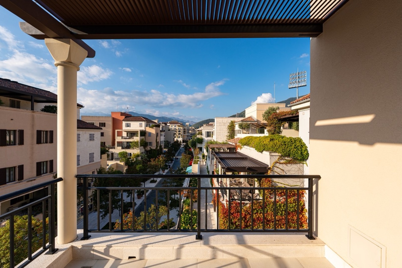 View from the apartment terrace in Porto Montenegro, Tivat, Montenegro: city street, modern architecture, and mountains.