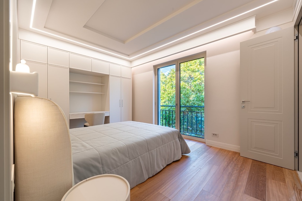 Modern bedroom in Porto Montenegro, Tivat, Montenegro: double bed, built-in wardrobe, and a view of greenery.