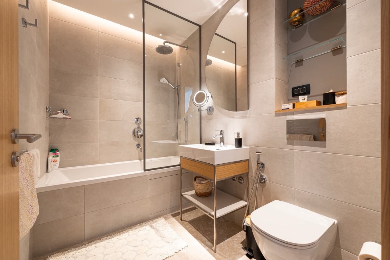 Modern bathroom in an apartment in Porto Montenegro, Tivat, Montenegro: light tiles, bathtub with glass screen, shower.