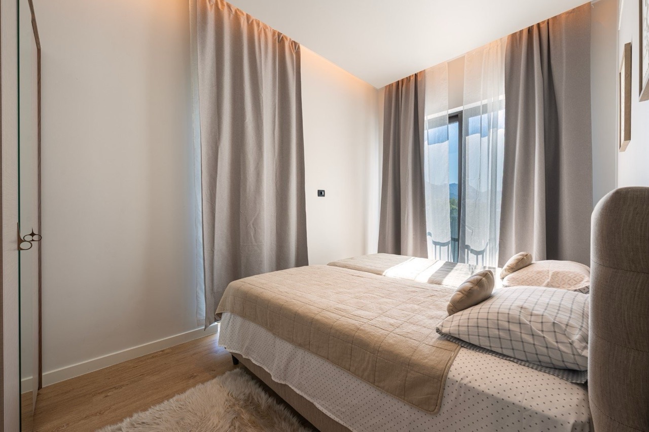Modern bedroom with a double bed in an apartment, Porto Montenegro, Tivat, Montenegro: bright interior, mountain view.