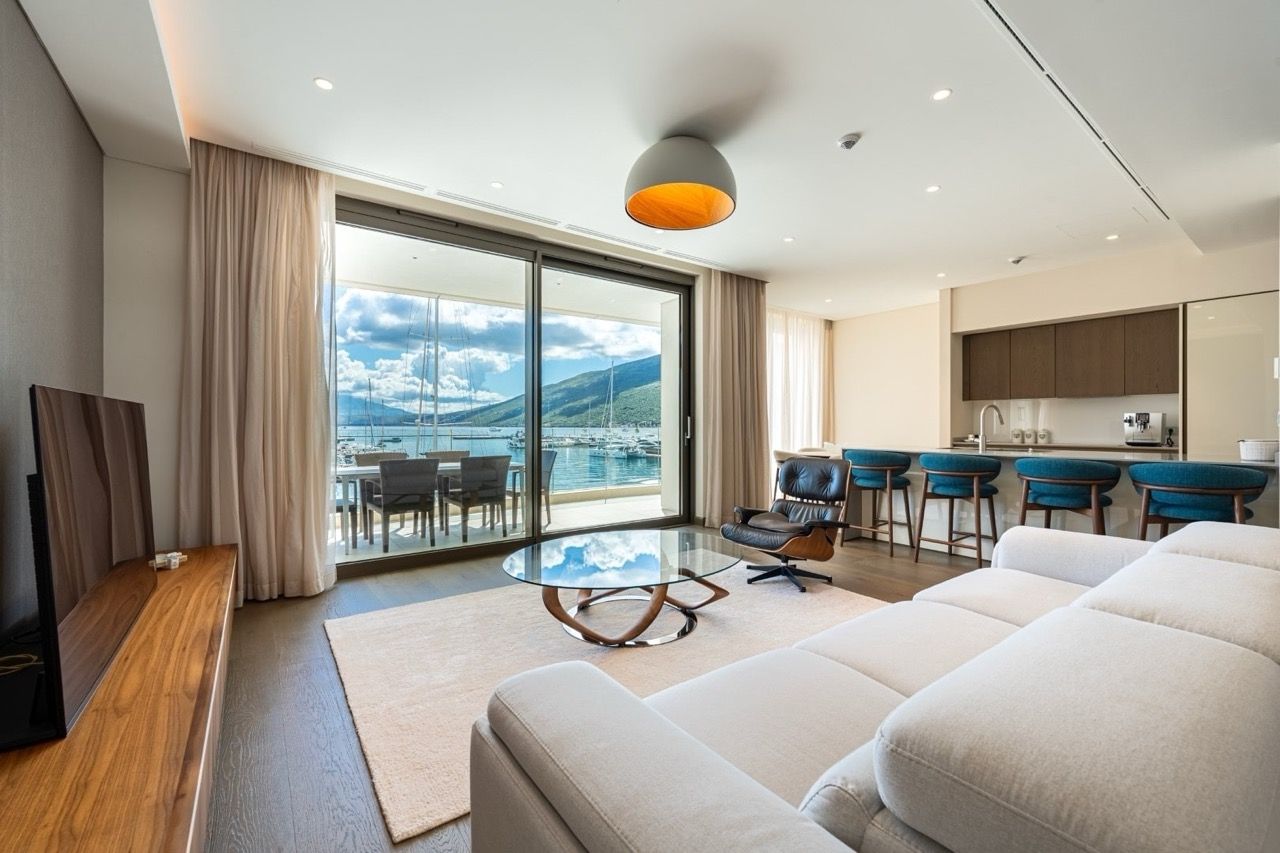 Living room with a view of the marina in Portonovi, Kumbor, Montenegro: modern furniture, panoramic windows, and an open-plan kitchen.