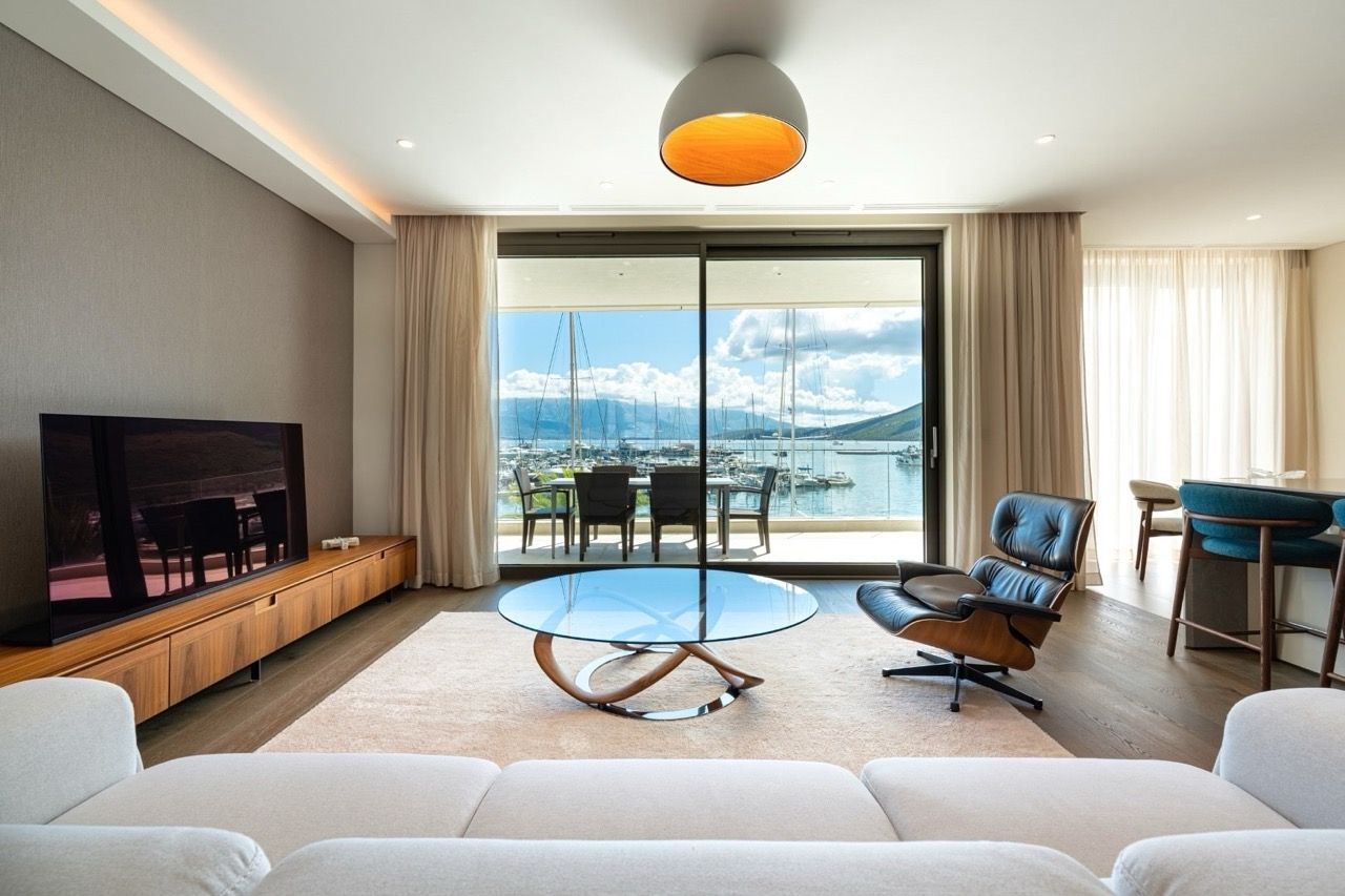 Living room in an apartment in Portonovi, Kumbor, Montenegro: modern interior, view of the marina with yachts, and a terrace.