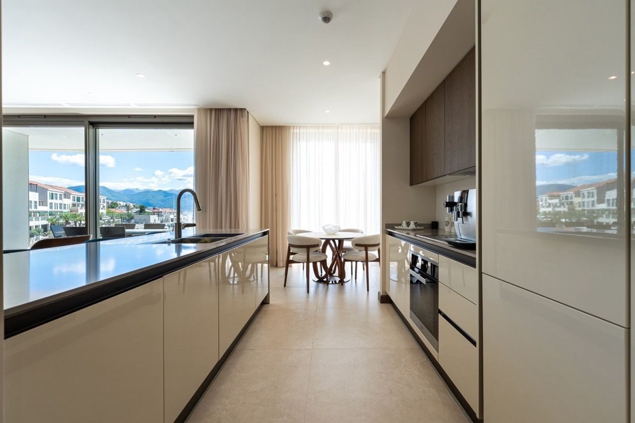 Modern kitchen in an apartment in Portonovi, Kumbor, Montenegro: glossy cabinets, dining area, and marina view.
