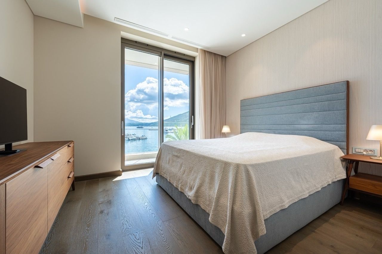 Modern bedroom in Portonovi, Kumbor, Montenegro with sea view, double bed, and wooden furniture.