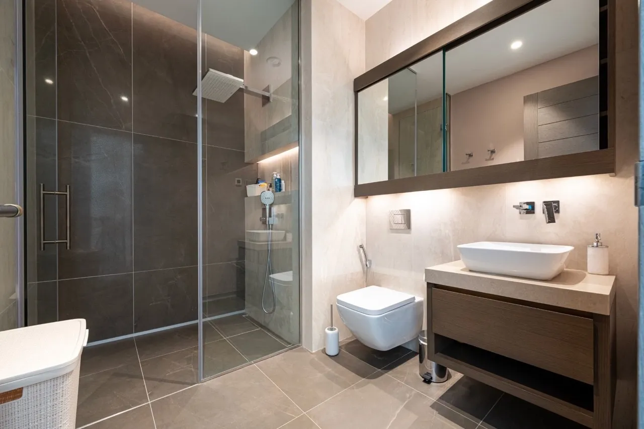 Modern bathroom featuring a glass-enclosed shower, wall-mounted toilet, and vanity with a vessel sink.