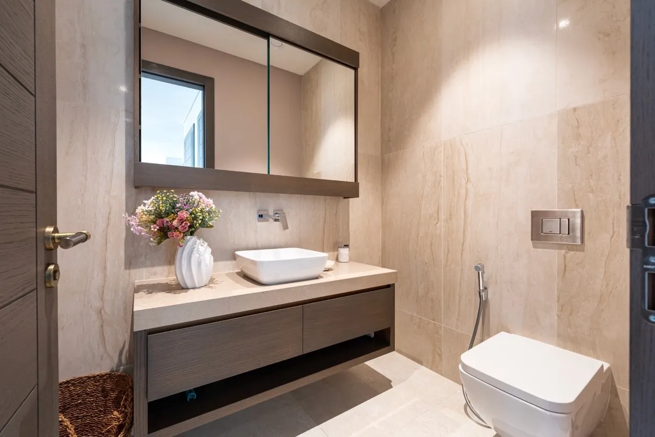 Modern bathroom featuring a wall-mounted toilet, vessel sink on a floating vanity, and a large framed mirror.
