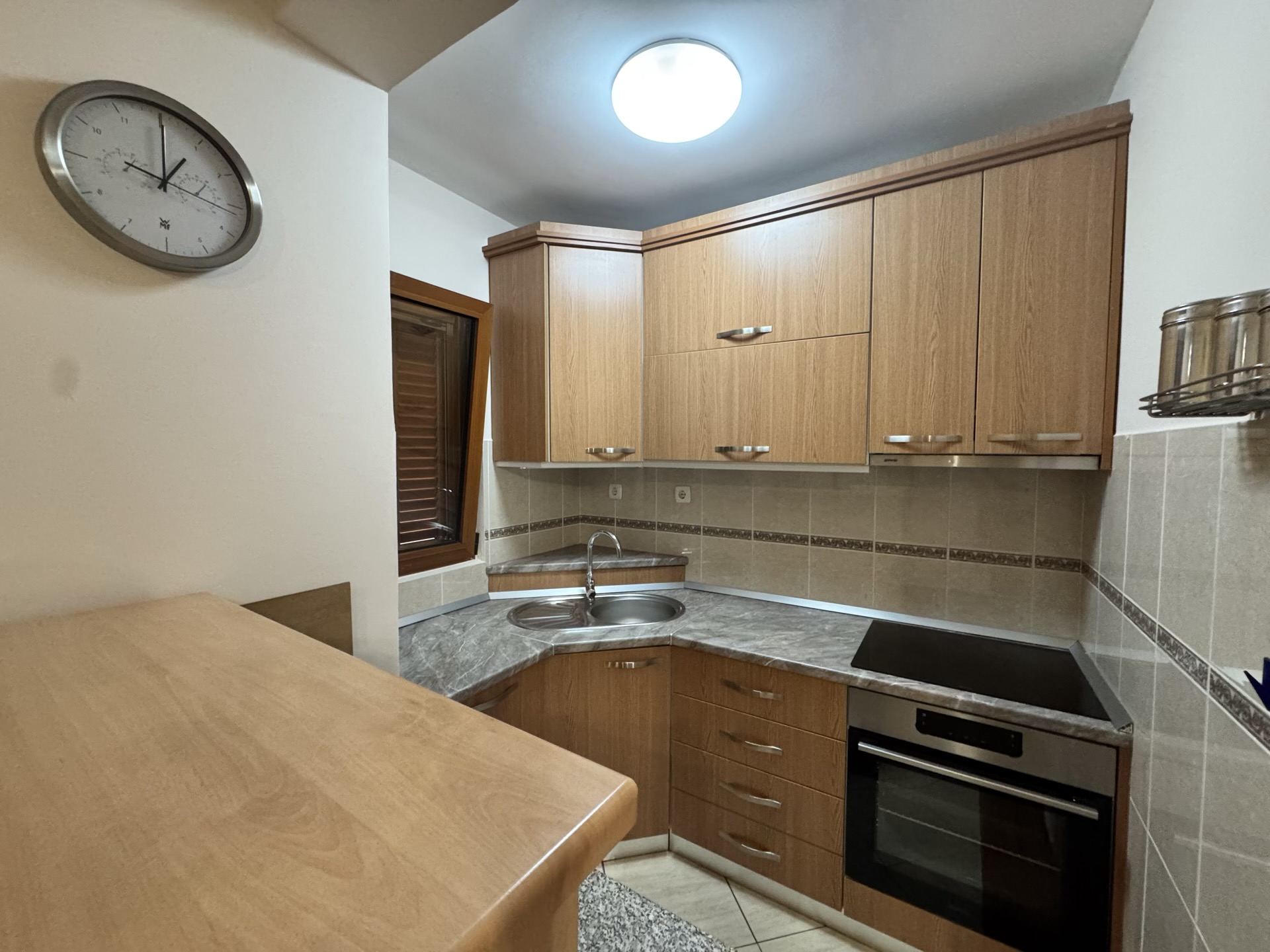 Corner kitchen with wooden fronts and built-in appliances in an apartment, Budva, Montenegro.