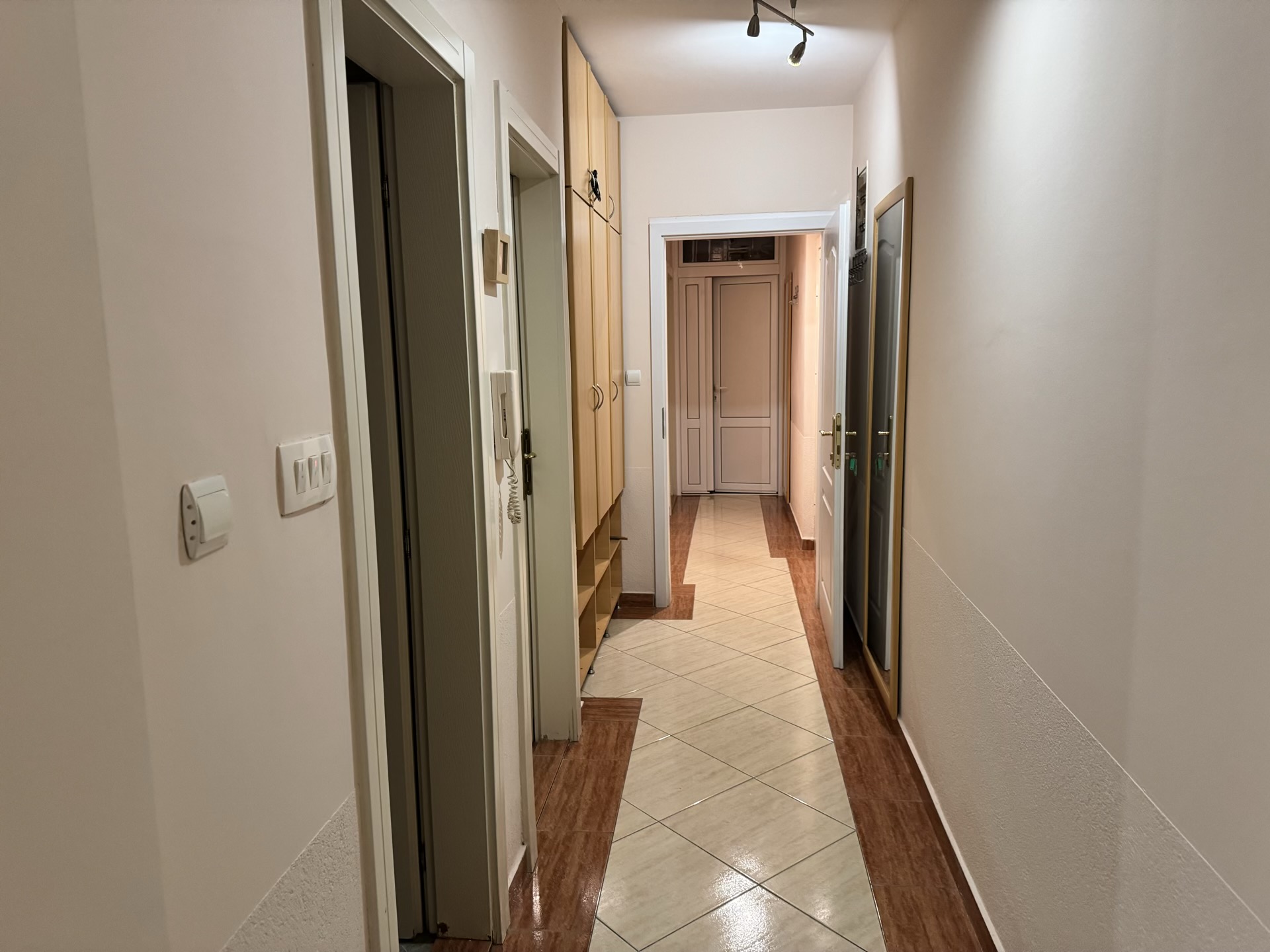Bright hallway in an apartment in Budva, Montenegro: built-in wardrobe, tiled floor, and interior doors.