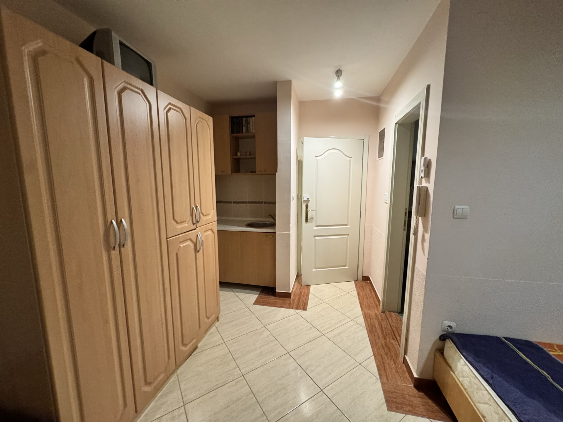 Compact kitchen in an apartment in Budva, Montenegro: light-colored cabinets, built-in wardrobe, and tiled hallway floor.
