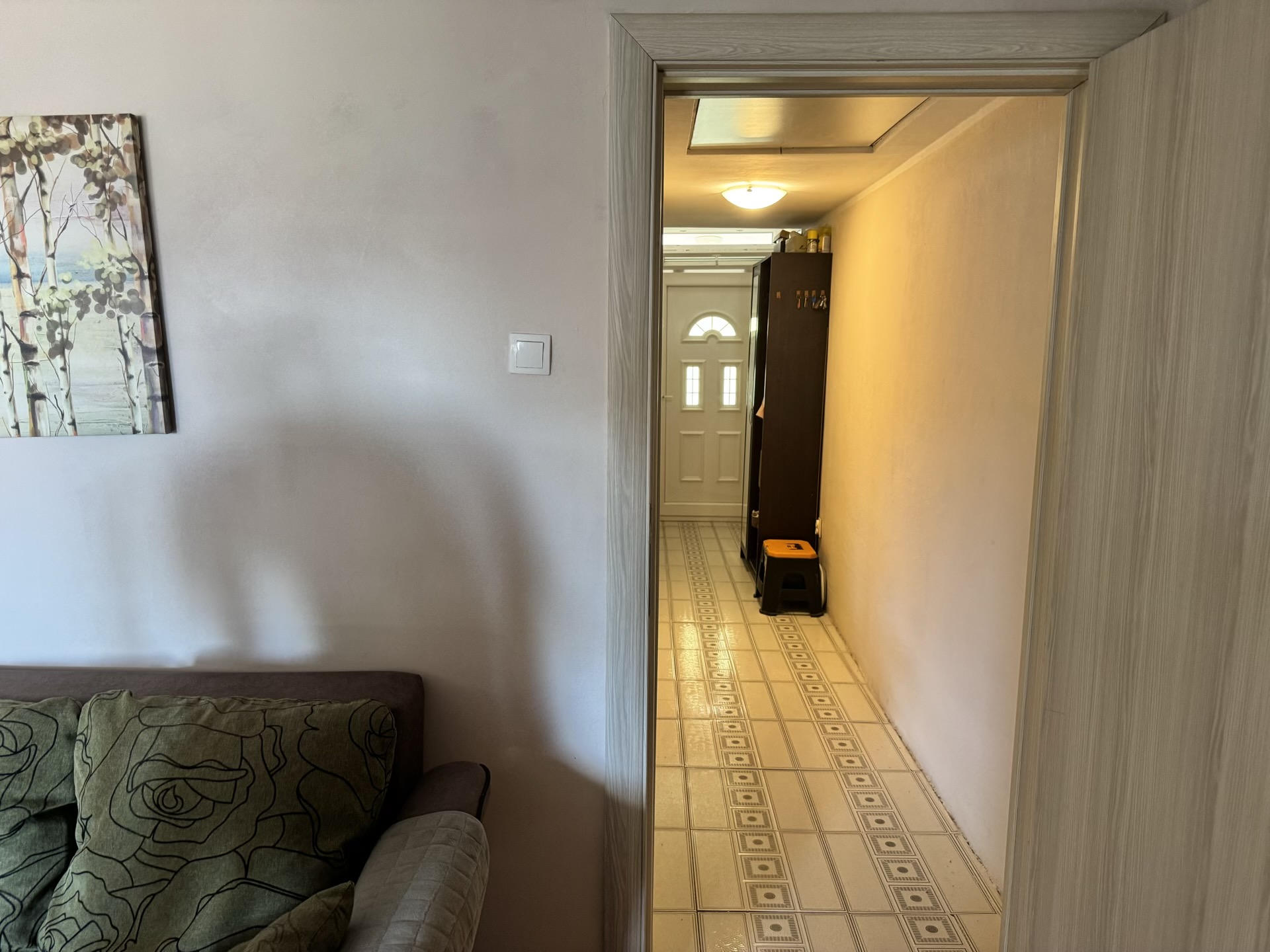 View from the living room into the apartment hallway in Bečići, Montenegro: light finishes, tiled floor, and the front door.
